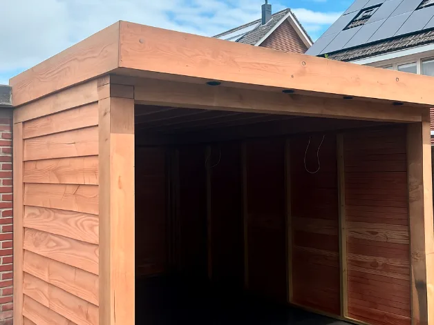 Douglas overkapping met dichte wanden van Douglas-planken en inbouwspots in de dakrand