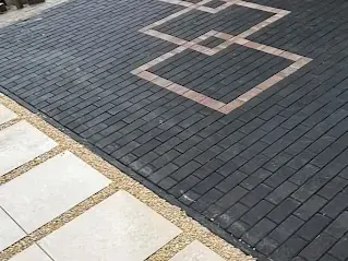 Sierband in zwart keperverband naast een tegelpad in split