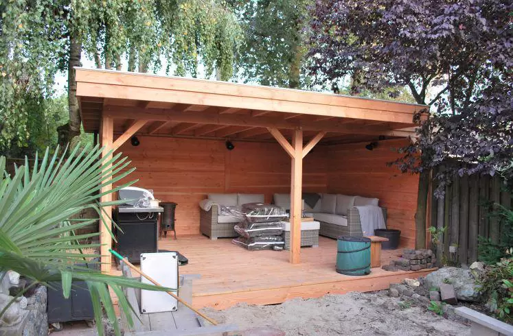 Ruime Douglas overkapping met plat dak en houten wanden, met een loungeset op een vlonder